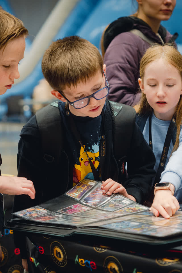 Three children heads-down over a trading binder, picking through the pages together.
