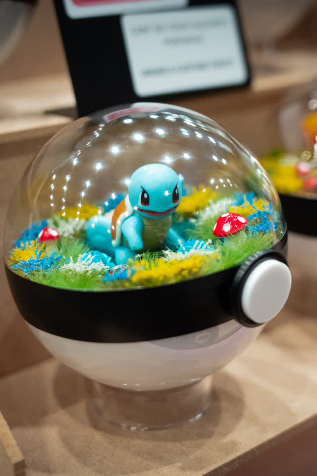 A handmade terrarium in a clear dome on a maker stand.