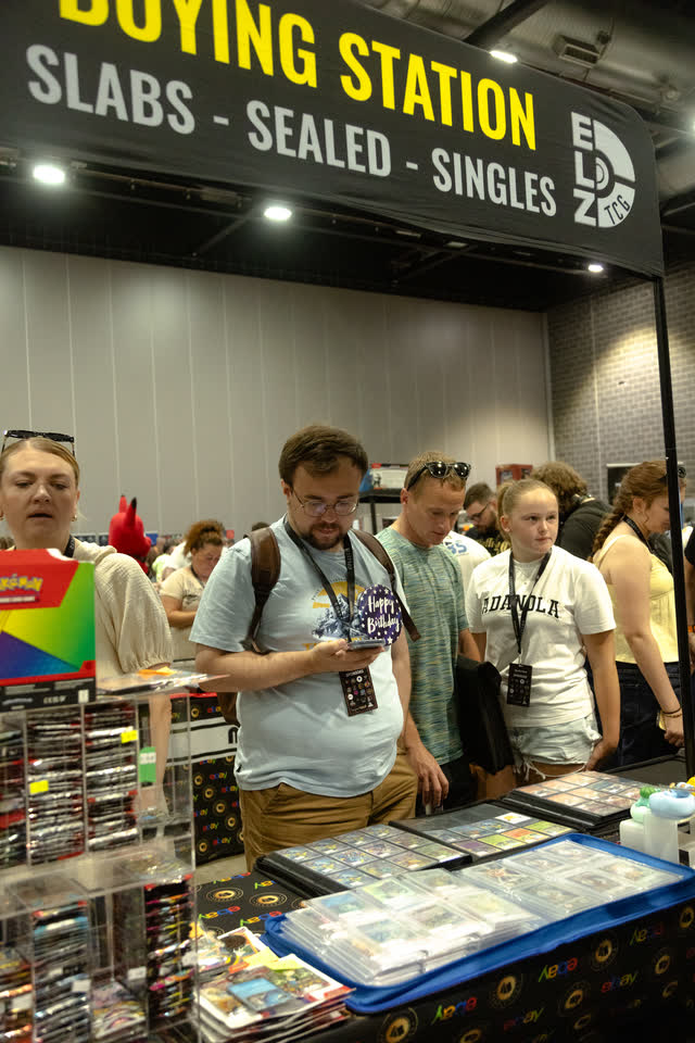 Collectors gathered at a buying station stand under a sign reading slabs, sealed, singles.