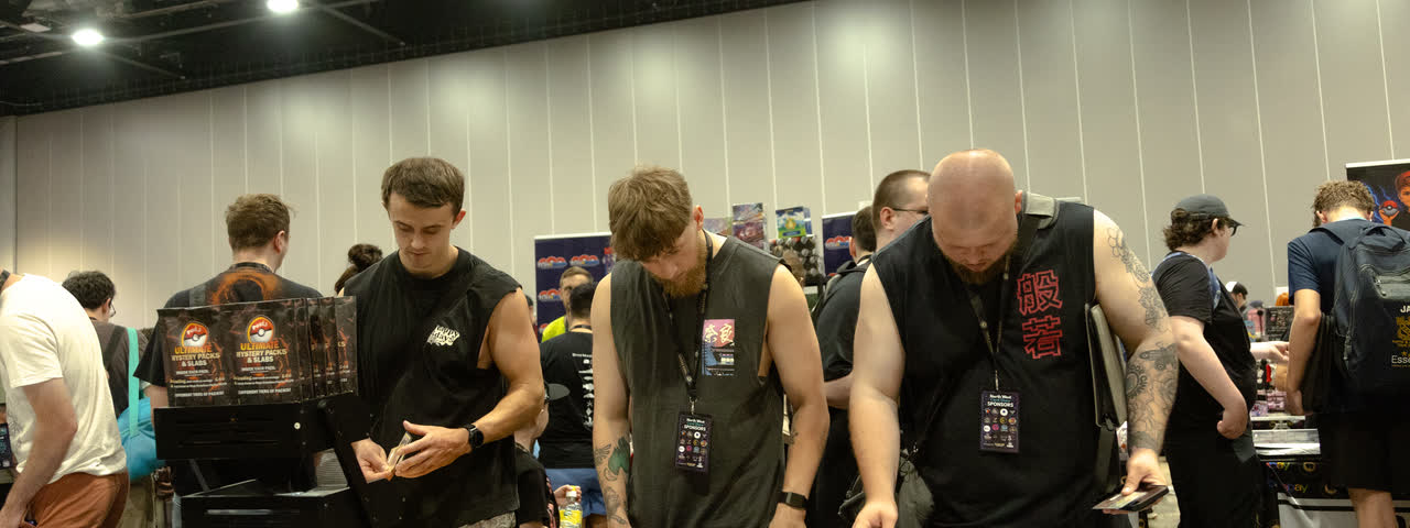 A row of collectors side by side along a table, each working through a binder.