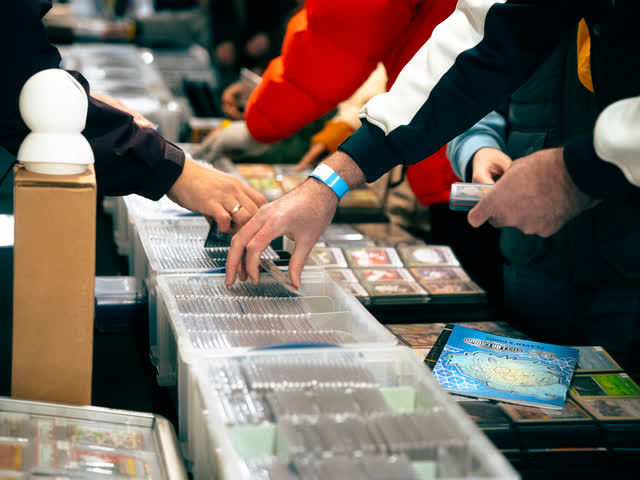 Hands reaching into long boxes of sleeved cards, digging for the right one.