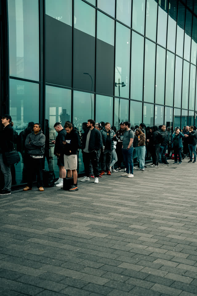 A long queue lined up along the glass front of the venue before the doors open.