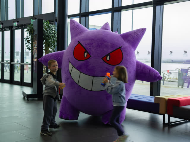 Two children playing with a giant inflatable Gengar by the venue windows.