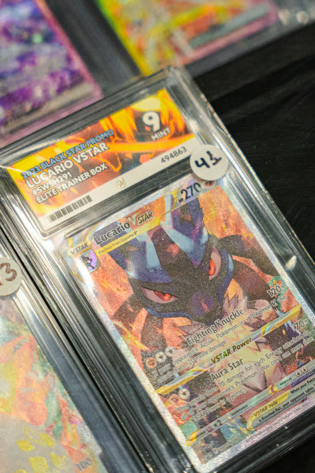 A graded Lucario card in its slab, close up on a vendor table.