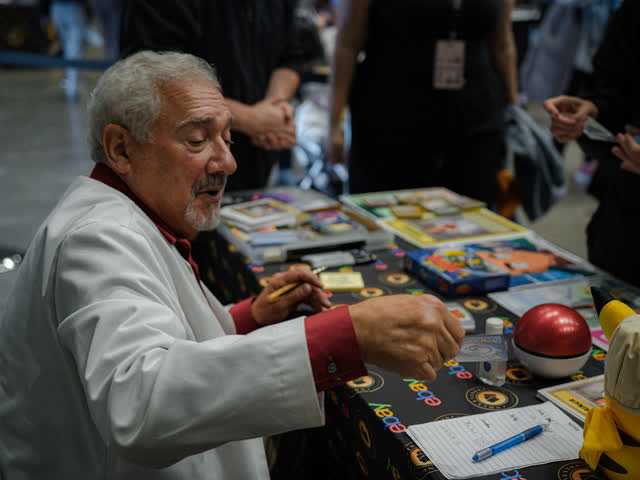 A guest in a white coat signing items at his table.