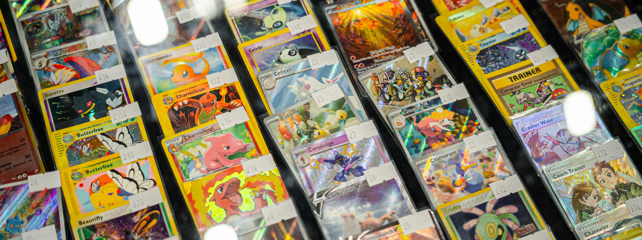 Rows of priced singles in top loaders filling a lit display case.