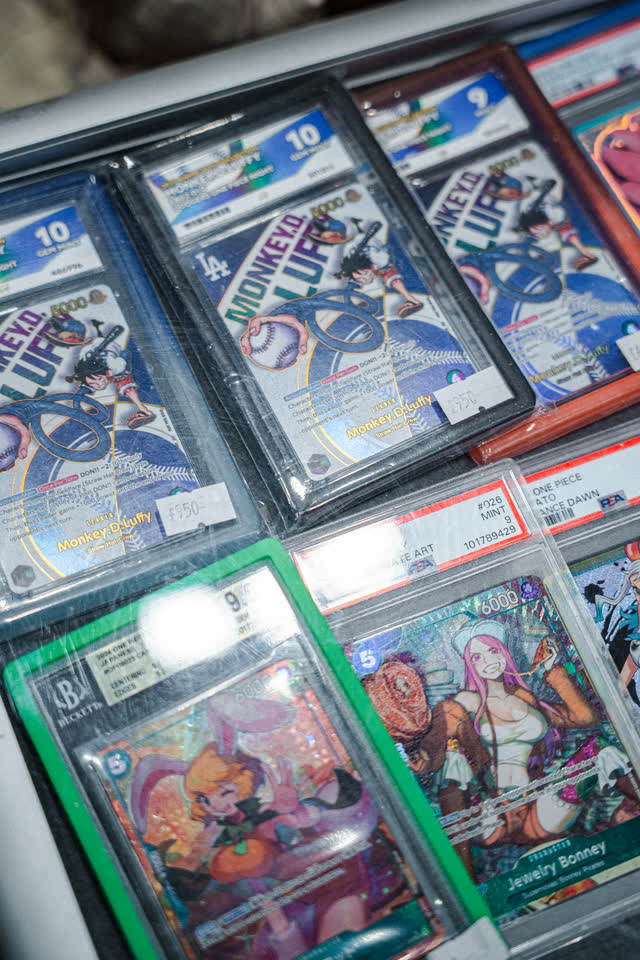 Graded One Piece cards in slabs on a vendor table.