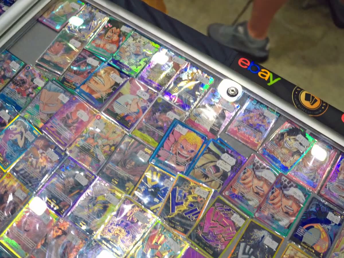 Light sweeping over a case of holographic cards on a vendor table.